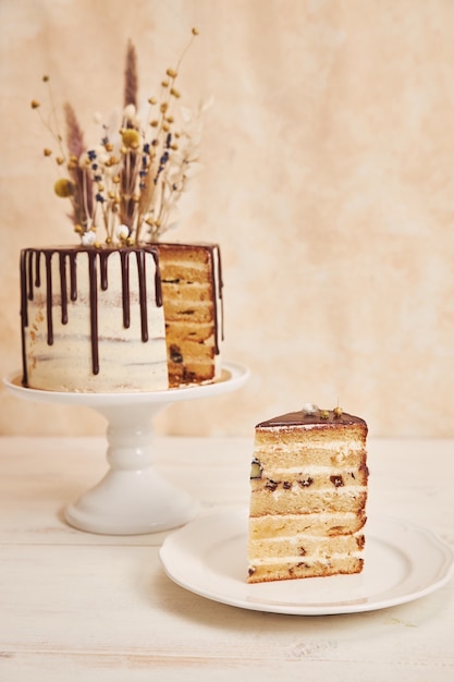 チョコレートのしずくと金色の装飾が施された花が上にあるおいしい自由奔放に生きるケーキの垂直ショット