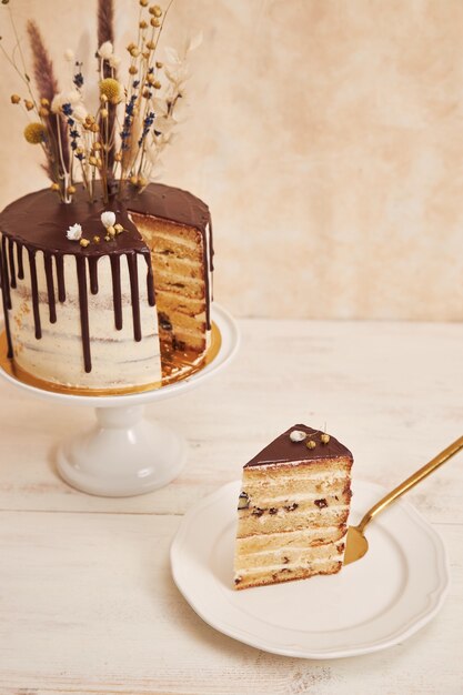 황금 장식으로 위에 초콜릿 드립과 꽃을 곁들인 맛있는 보헤미안 케이크의 세로 샷