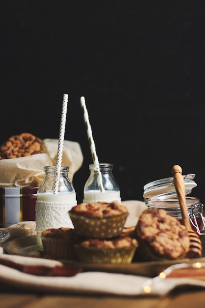 Vertical shot of delicious Christmas cookie muffins on a plate with honey and milk on a wooden table