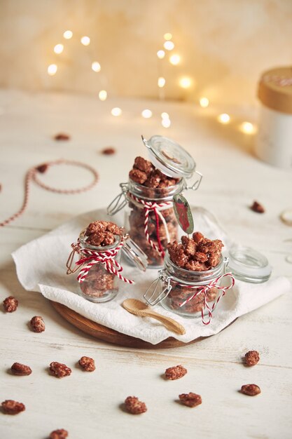 Vertical shot of delicious Christmas roasted almonds in a jar on a wooden plate