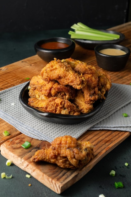 Free photo vertical shot of delicious crispy fried chicken, ketchup, gravy and celery sticks on a wooden table