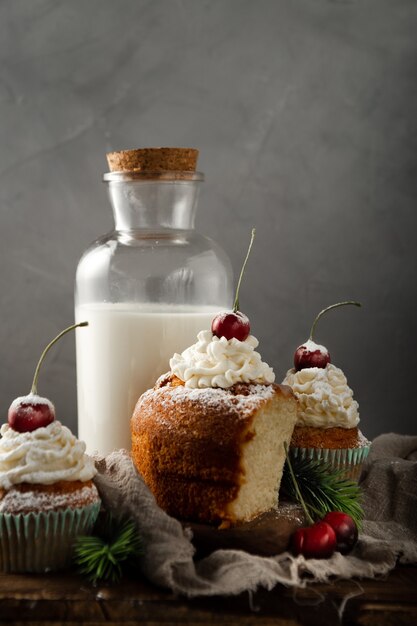 가루 설탕과 함께 맛있는 컵 케이크의 세로 샷과 우유 위에 체리