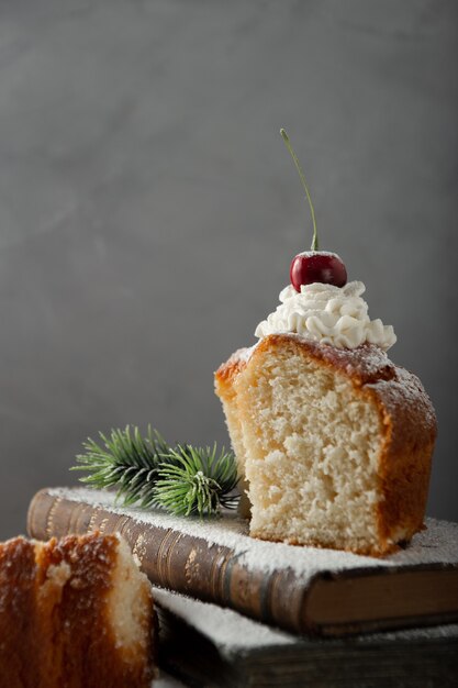 Vertical shot of delicious dessert with cream, powdered sugar, and a cherry on top on books