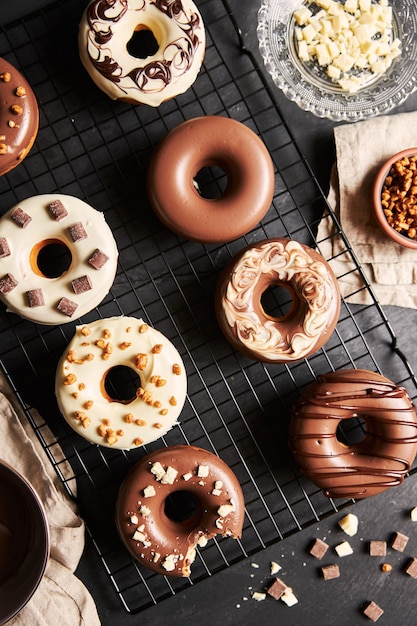 Vertical shot of delicious donuts covered in the white and brown chocolate glaze on a black table