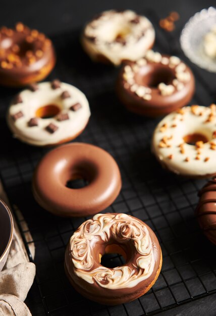 Vertical shot of delicious donuts covered in the white and brown chocolate glaze on a black table