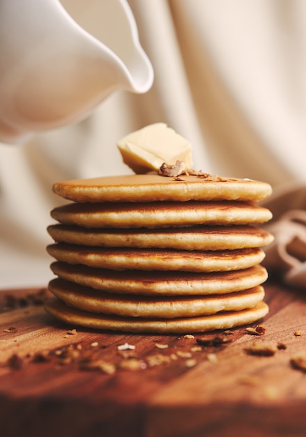 Vertical shot of delicious pancakes with butter, figs, and roasted nuts on a wooden plate