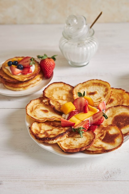 Vertical shot of Delicious Pancakes with fruits on a white wood Table