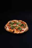 Foto gratuita ripresa verticale di una deliziosa pizza su una superficie nera