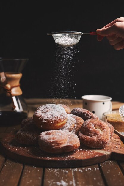 가루 설탕과 케멕스 커피를 뿌린 맛있는 뱀 도넛의 세로 샷