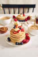 Free photo vertical shot of delicious vegan tofu pancakes with colorful fruits near syrup  and coffee
