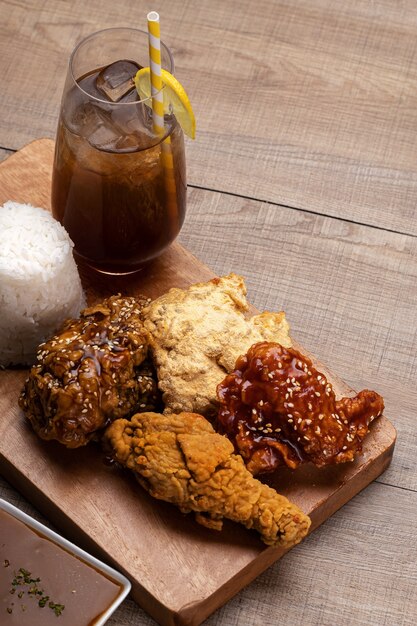 Vertical shot of deliciously cooked chicken wings with sauce and sesame on a tray with a cold drink