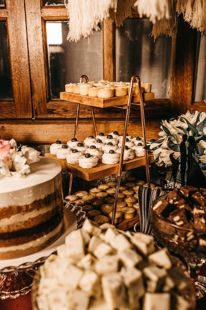 Vertical shot of a dessert table with various delicious pastries under the light