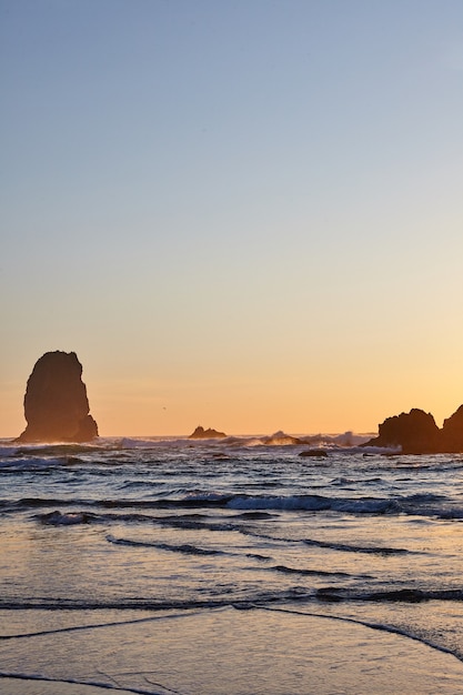 Vertical shot of the famous Haystack Rock on the rocky shoreline of the Pacific Ocean