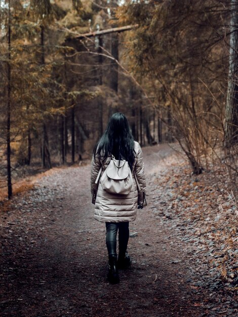 森の中の小道を歩いている女性のバックパッカーの垂直ショット