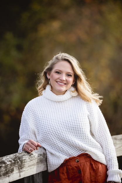 Vertical shot of a female leaning against a wooden fence while smiling