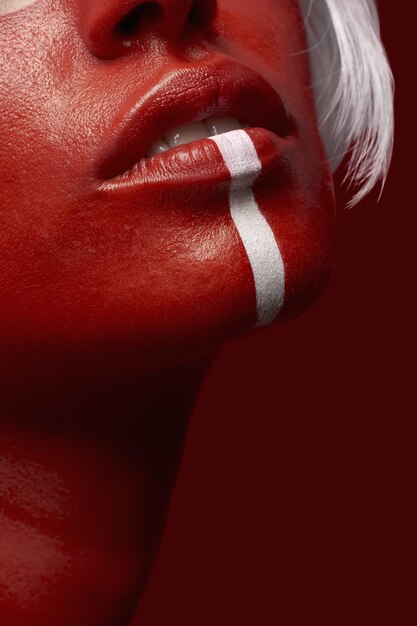 Vertical shot of a female in red body paint with a white line on a red