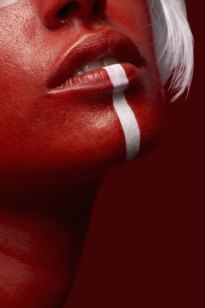 Vertical shot of a female in red body paint with a white line on a red