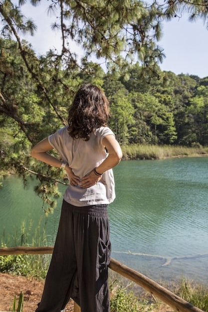 Vertical shot of a female standing in front of the lake of Montebello, Chiapas, Mexico