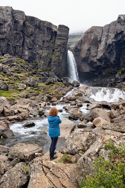 Vertical shot of female taking a picture of Breidafjordur bay in Iceland