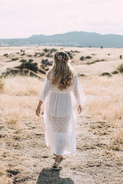 Free photo vertical shot of a female wearing a nice white dress in the middle of a meadow