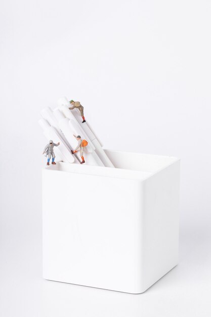 Vertical shot of figurines of students climbing on pens in a pot