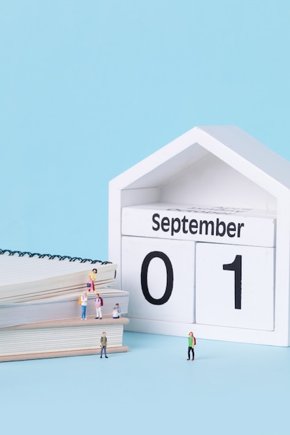 Vertical shot of figurines of students standing on around textbooks on the first day of school