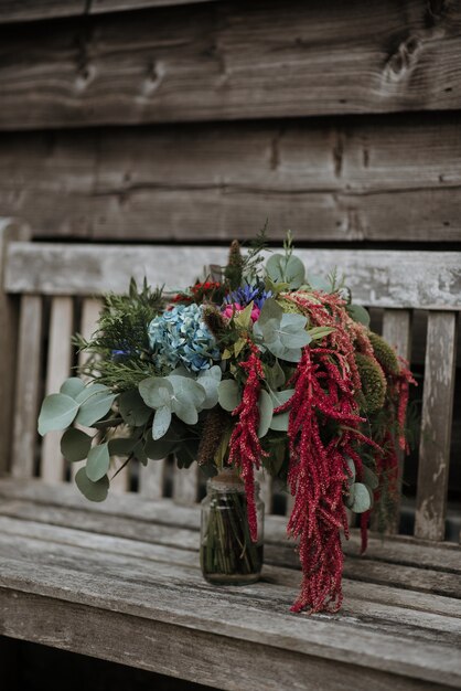 Vertical shot of a flower bouquet in a glass vase on a wooden bench