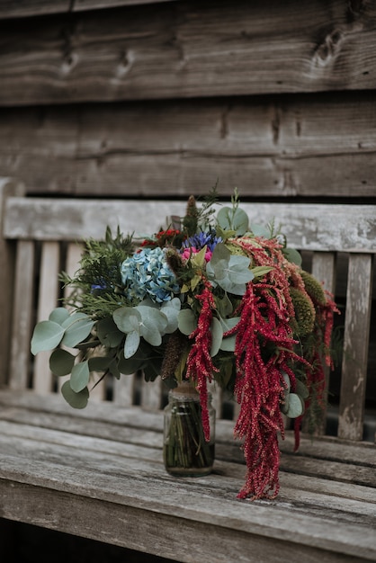 Vertical shot of a flower bouquet in a glass vase on a wooden bench