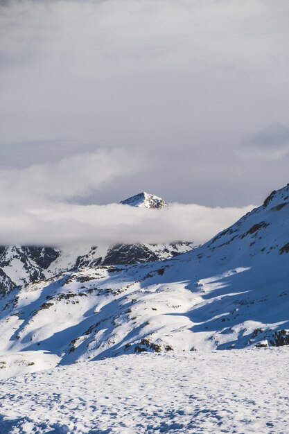 Vertical shot of fog on the mountains covered in snow