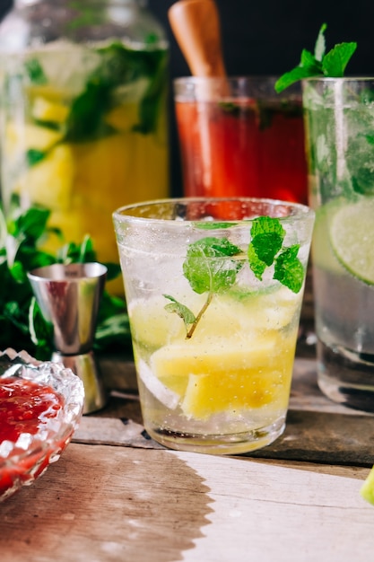 Vertical shot of freshly-made cold drinks with fruits and mint on the table