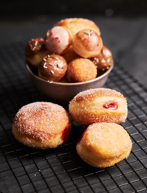 Вертикальный снимок жареных пончиков с сахаром и сливками на черном столе