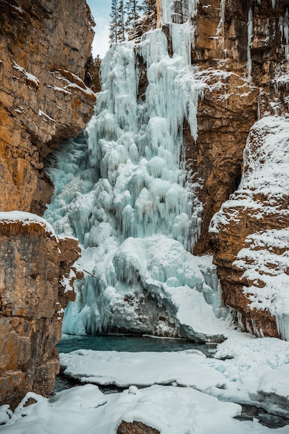 Vertical shot of a frozen waterfall surrounded by rock formations