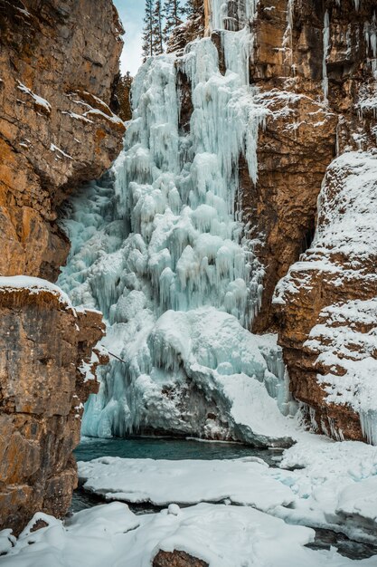 Вертикальный снимок замерзшего водопада в окружении скальных образований