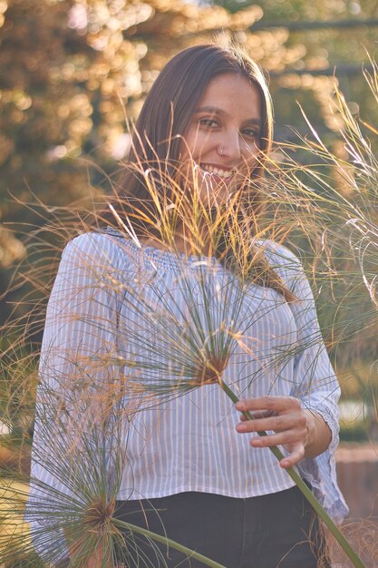 薄い植物の葉を通してカメラを見ている女の子の垂直ショット