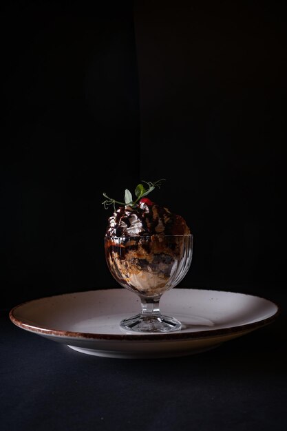 Vertical shot of a glass of delicious ice-cream with chocolate syrup and whipped cream