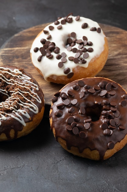 Colpo verticale di ciambelle glassate condite con gocce di cioccolato su una superficie rustica