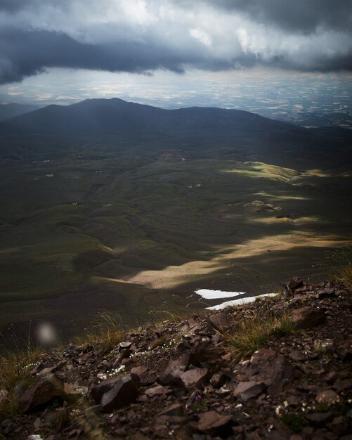 Vertical shot of grassy hills under a cloudy sky