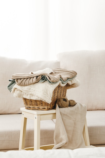 Free photo vertical shot of a gray sofa with a basket of folded clothes on a small table near it