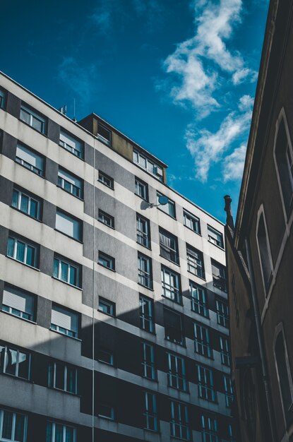 Vertical shot of a gray and white building with windows under a blue sky