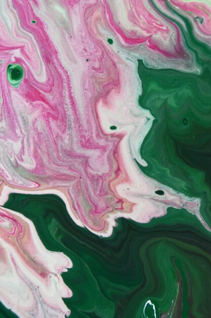 Вертикальный снимок зеленых, розовых и белых абстрактных узоров с красками в воде