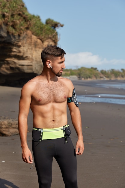 Free photo vertical shot of half naked healthy male athlete takes break after workout