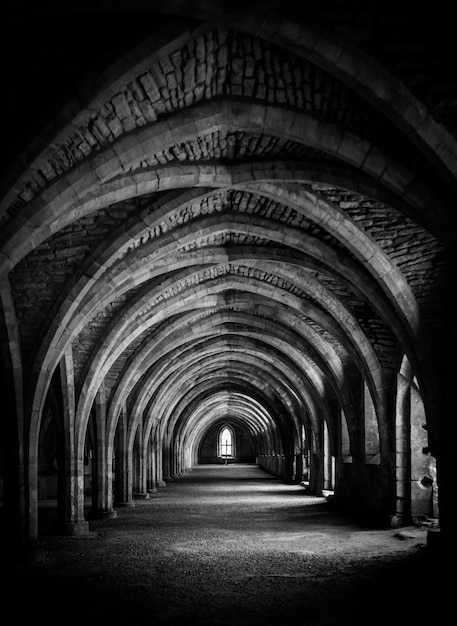 Vertical shot of hallway in black and white at the crypt at Fountains Abbey.