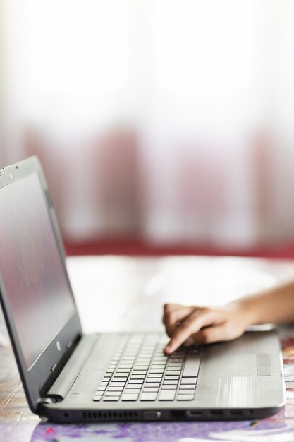 Vertical shot of the hand of a person typing on a laptop