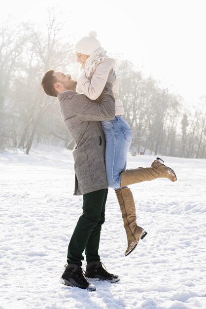 추운 겨울 날 아름다운 눈을 즐기는 행복한 커플의 세로 샷