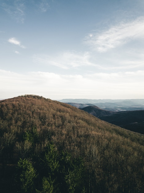 Free photo vertical shot of a hill under the cloudy blue sky at daytime