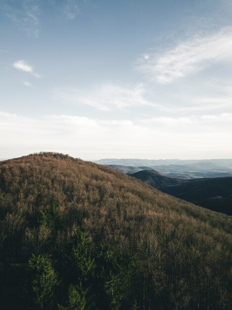 Vertical shot of a hill under the cloudy blue sky at daytime