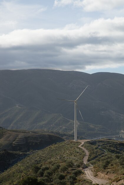曇り空の下で背景に風車のある緑に覆われた丘の垂直ショット