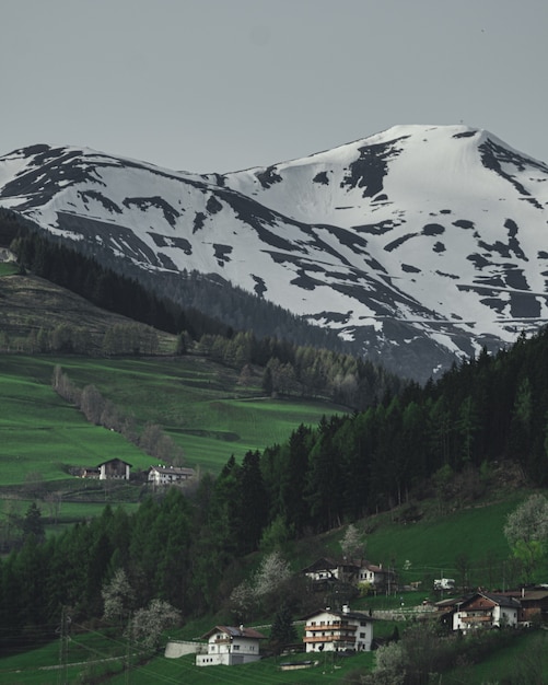 Colpo verticale delle case su una collina con la bella montagna innevata