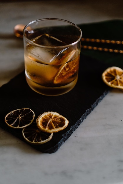Vertical shot of an iced cocktail with dried lemons on a black board