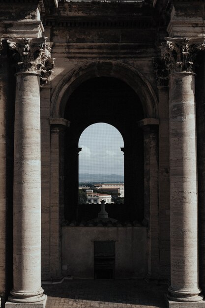 Vertical shot of the inside of a temple with arch window and the beautiful cityscape in background